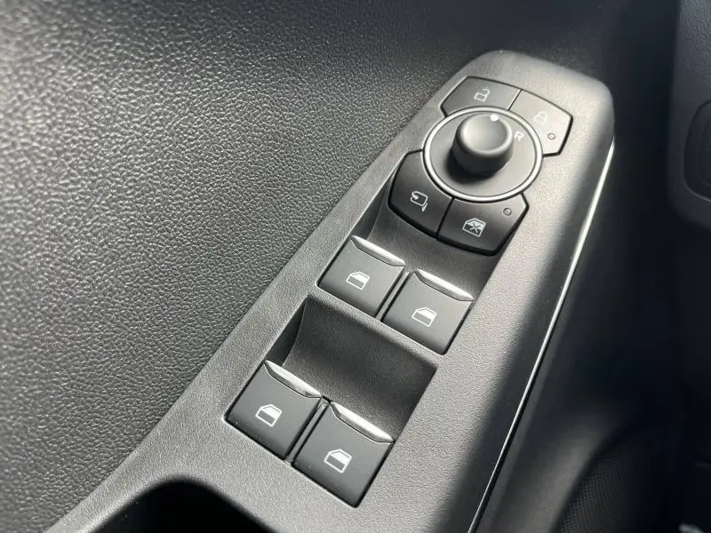 Commandes électriques des vitres et rétroviseurs sur la porte côté conducteur d'un Ford Puma bleu 2023 Titanium.