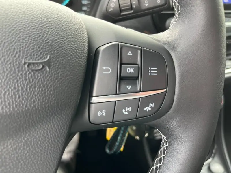 Gros plan sur les commandes multifonctions à droite du volant en cuir noir du Ford Puma bleu 2023.
