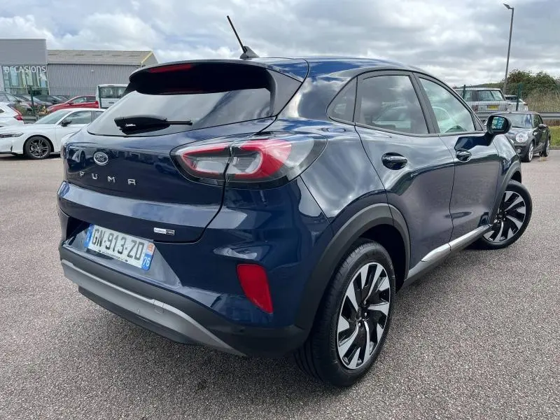 Vue 3/4 arrière droite d'un Ford Puma bleu Abysse avec vitres arrière surteintées et jantes alliage noires.