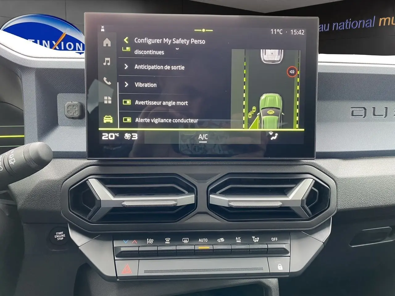 Vue intérieure du tableau de bord du Dacia Duster gris schiste 2025, avec écran tactile affichant les réglages de sécurité.