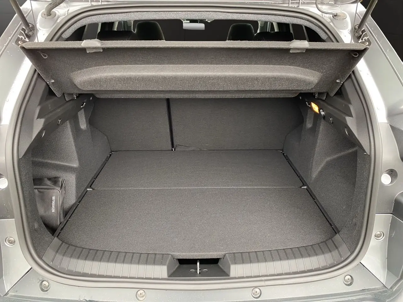 Coffre ouvert du Dacia Duster Full Hybrid 140 Journey 2025 gris schiste, vue arrière montrant l’espace de chargement plat.