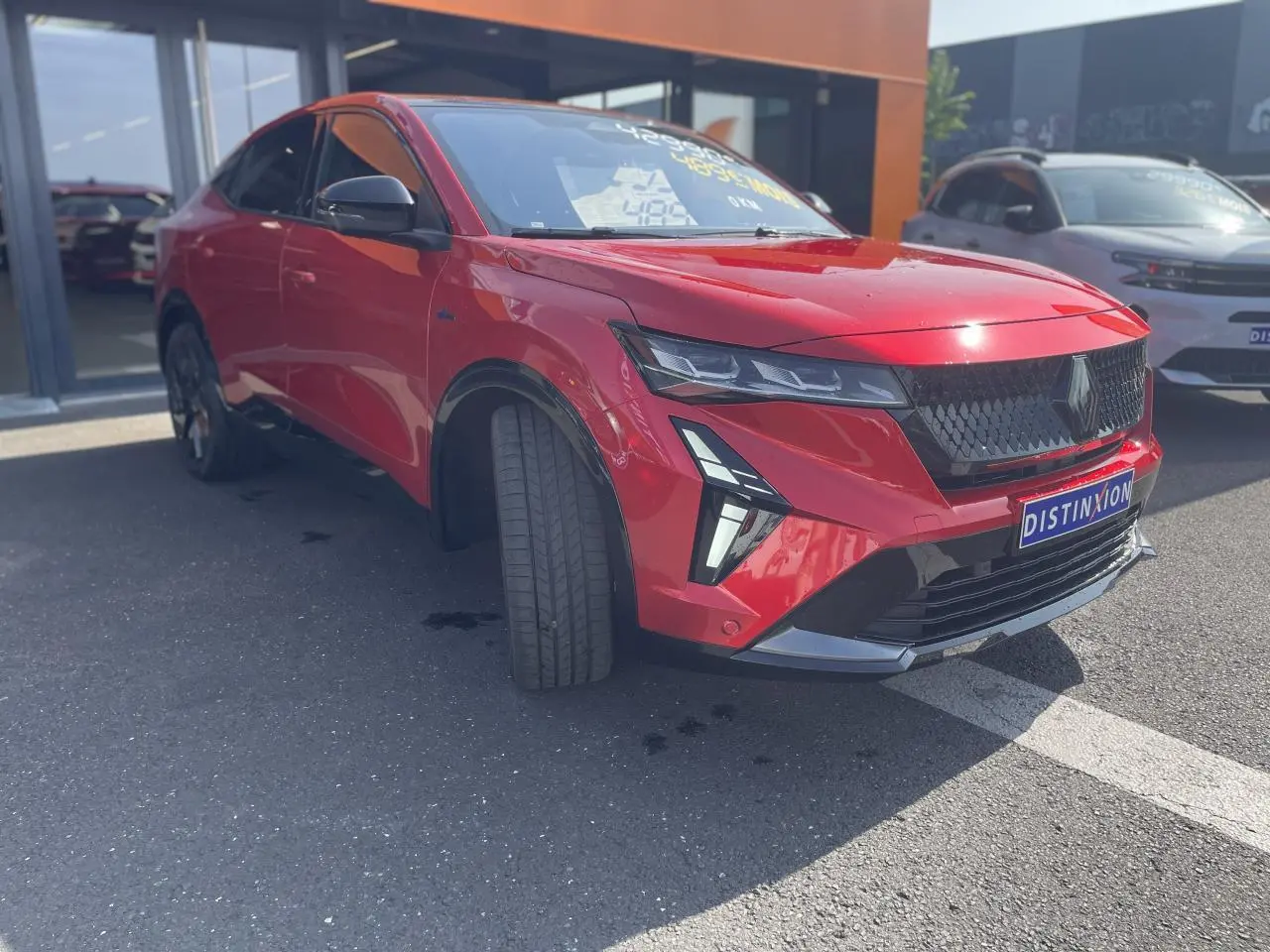 Vue 3/4 avant droit d'une Renault Rafale rouge flamme avec toit noir et calandre noire distinctive.