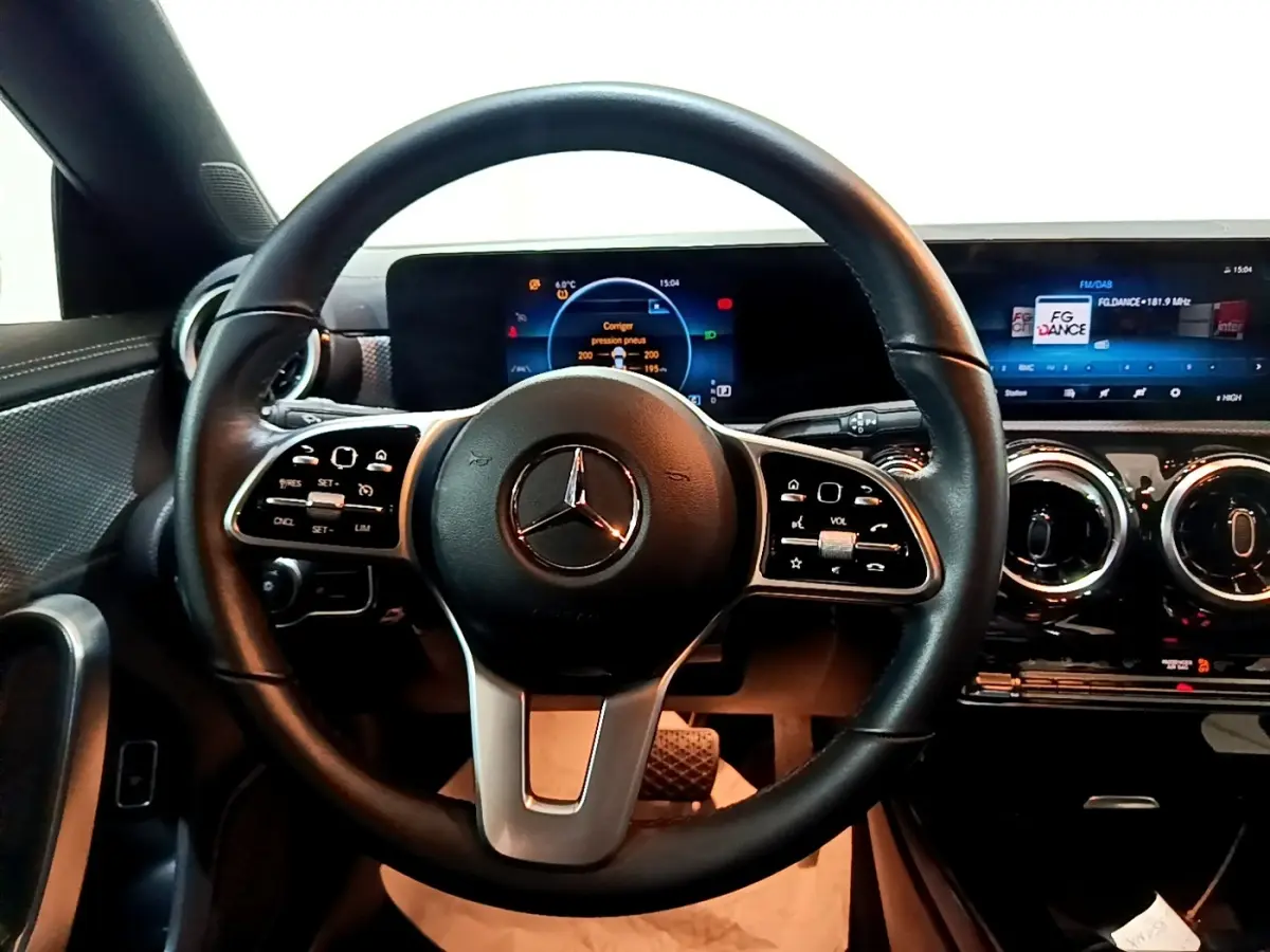 Vue intérieure centrée sur le volant cuir noir et le tableau de bord numérique de la Mercedes CLA 200 d Business Line.