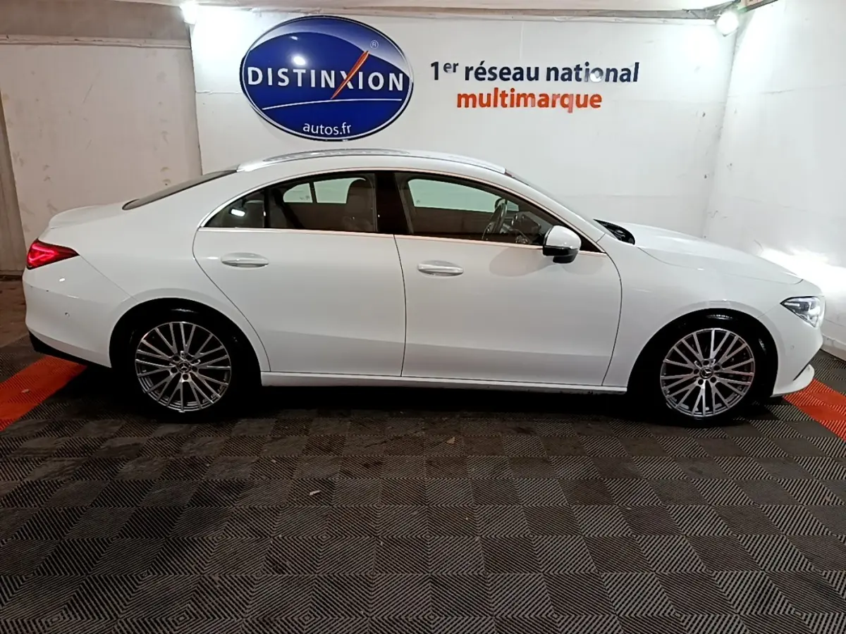 Vue latérale droite d'une Mercedes CLA 200 d Business Line blanche, avec jantes alliage et feux arrière allumés.