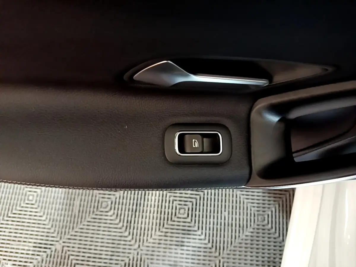 Détail de la poignée intérieure et bouton de verrouillage sur la porte côté gauche d’une Mercedes CLA 200 d Business Line blanche.