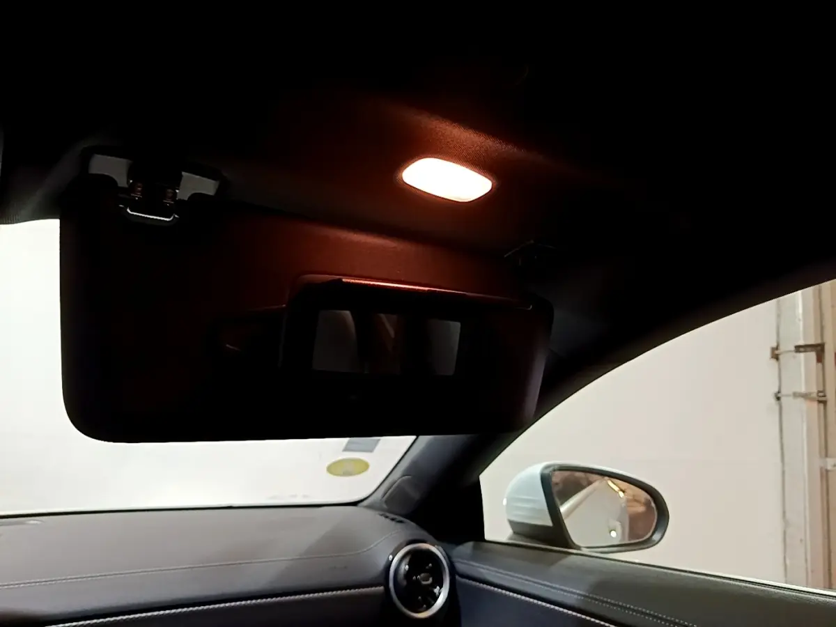 Intérieur de Mercedes CLA 200 d blanc, vue côté droit sur pare-soleil avec miroir éclairé et rétroviseur extérieur.