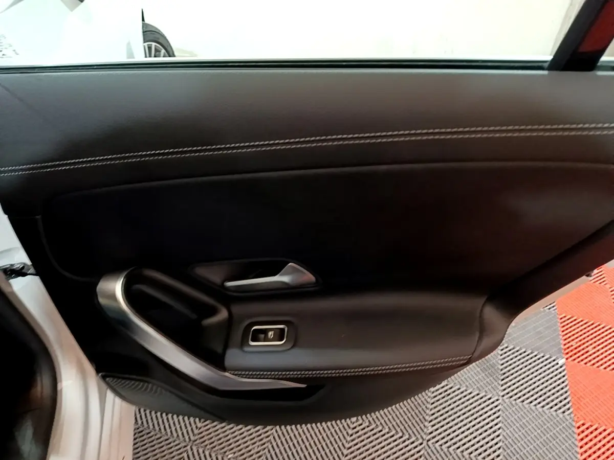 Vue rapprochée du panneau de porte intérieur côté gauche noir avec surpiqûres blanches d'une Mercedes CLA 200 d Business Line blanche.