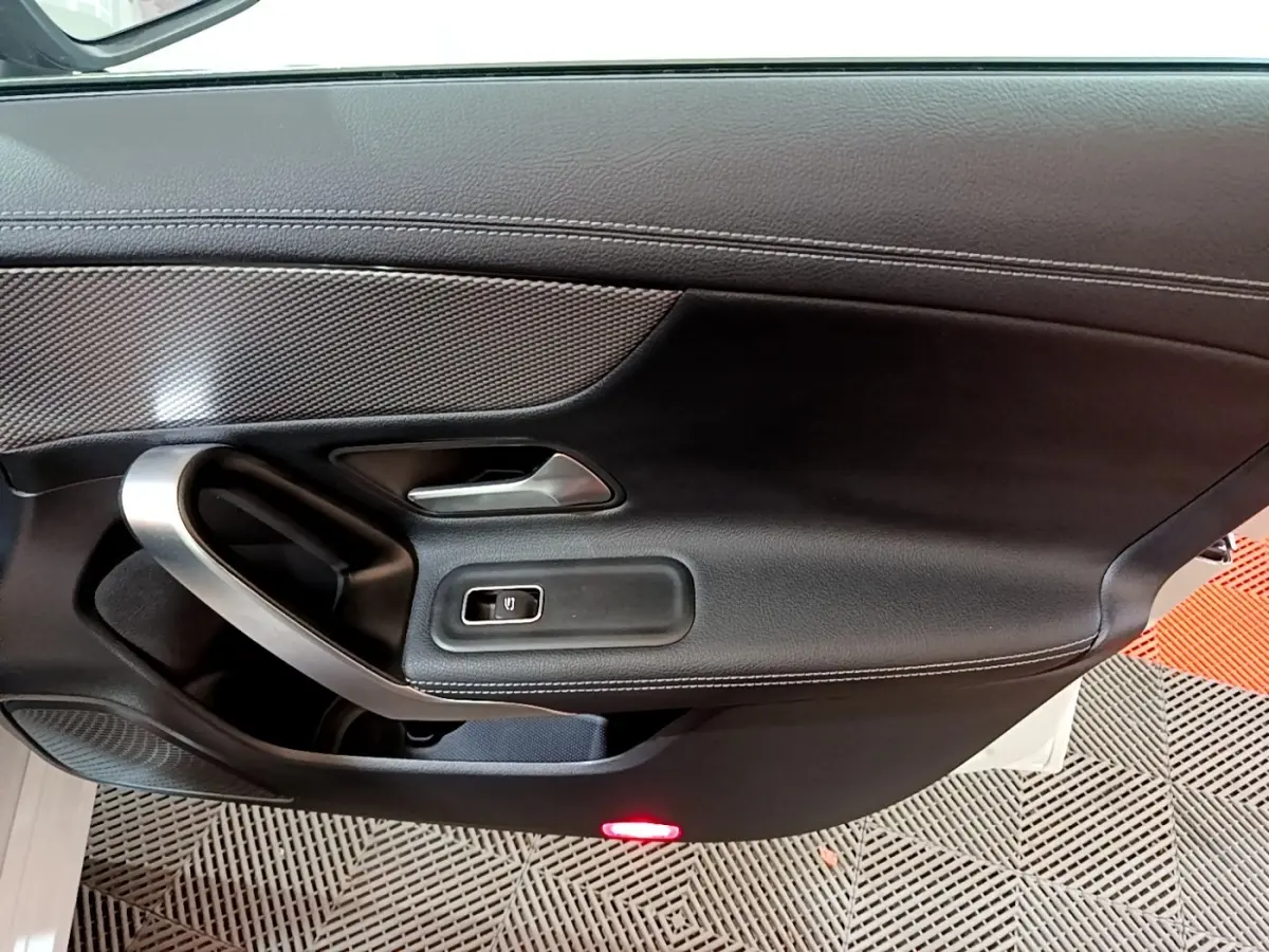 Vue rapprochée de la porte côté gauche noire de la Mercedes CLA 200 d Business Line avec poignée alu et bouton de vitre électrique.