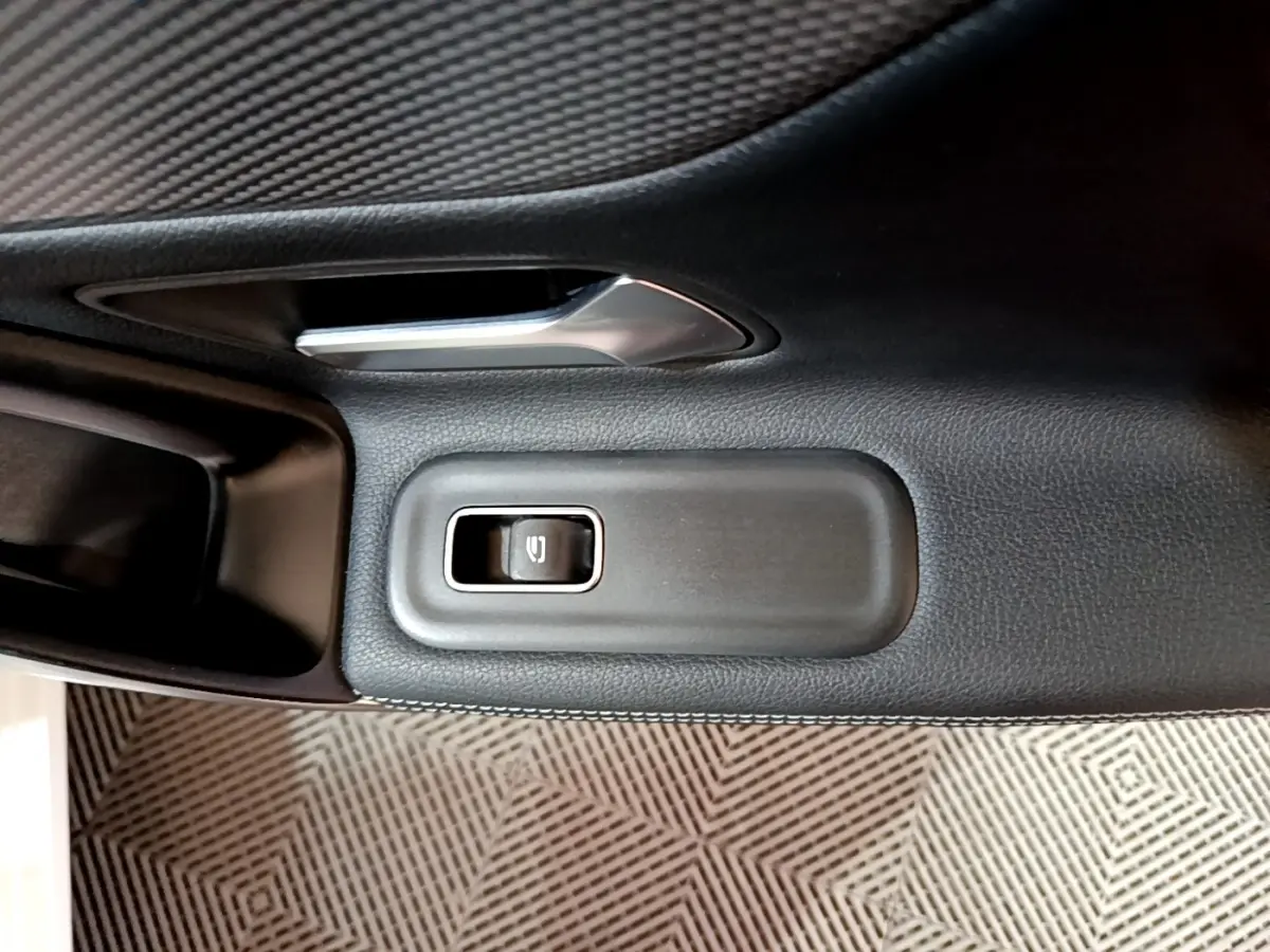 Détail du bouton de commande de la vitre électrique sur la porte intérieure côté conducteur d’une Mercedes CLA 200 d blanche.