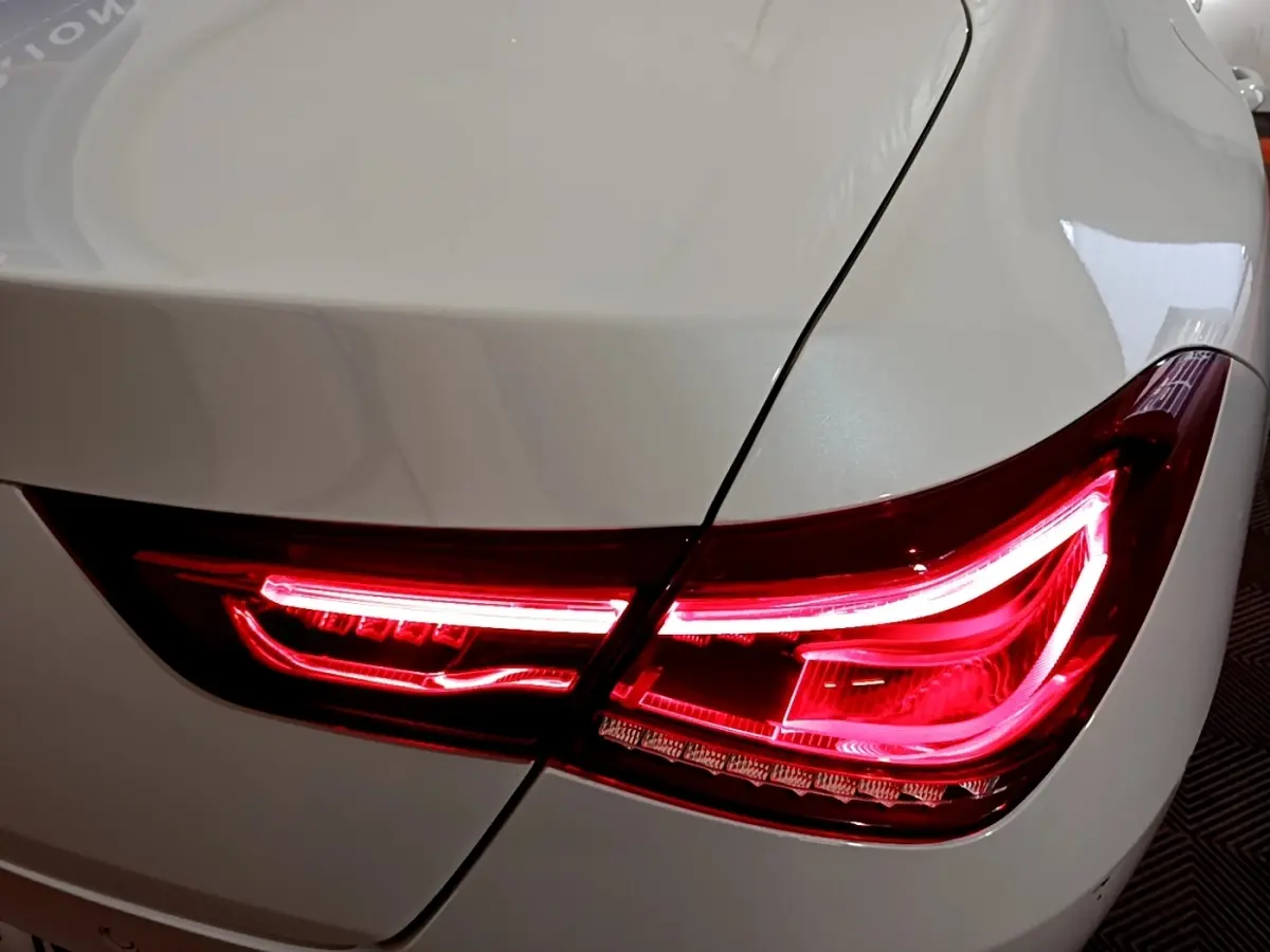 Gros plan sur le feu arrière droit rouge allumé d’une Mercedes CLA 200 d Business Line blanche.