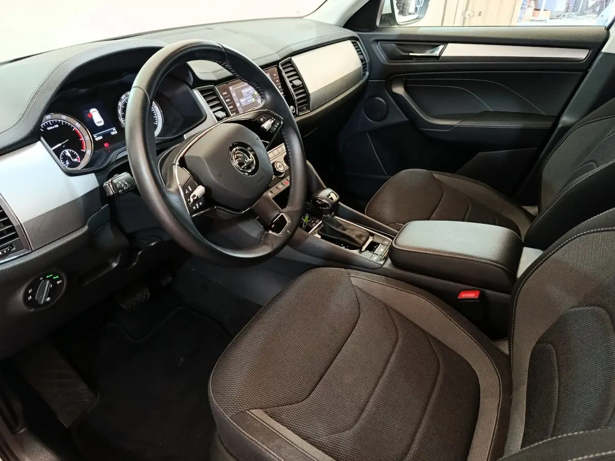 Intérieur avant droit du Skoda Kodiaq blanc 2022, avec tableau de bord digital et volant cuir multifonctions.