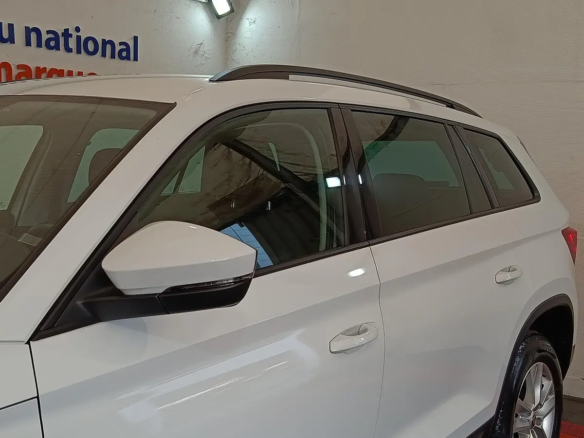 Vue de côté droit du SUV SKODA KODIAQ blanc 2022, mettant en valeur les rétroviseurs et les barres de toit noires.