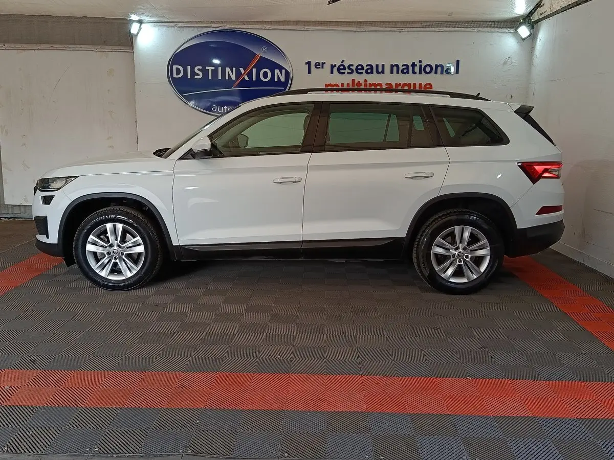 Vue de profil côté gauche d’un Skoda Kodiaq blanc 7 places, stationné en intérieur avec jantes alliage.