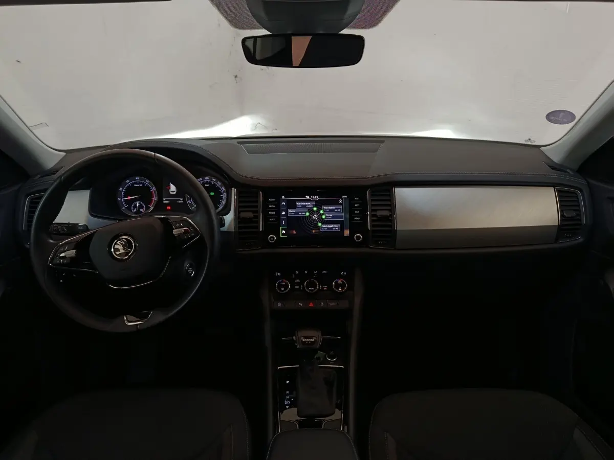 Vue intérieure frontale du tableau de bord noir du Skoda Kodiaq 2022 avec écran tactile central et volant multifonctions.