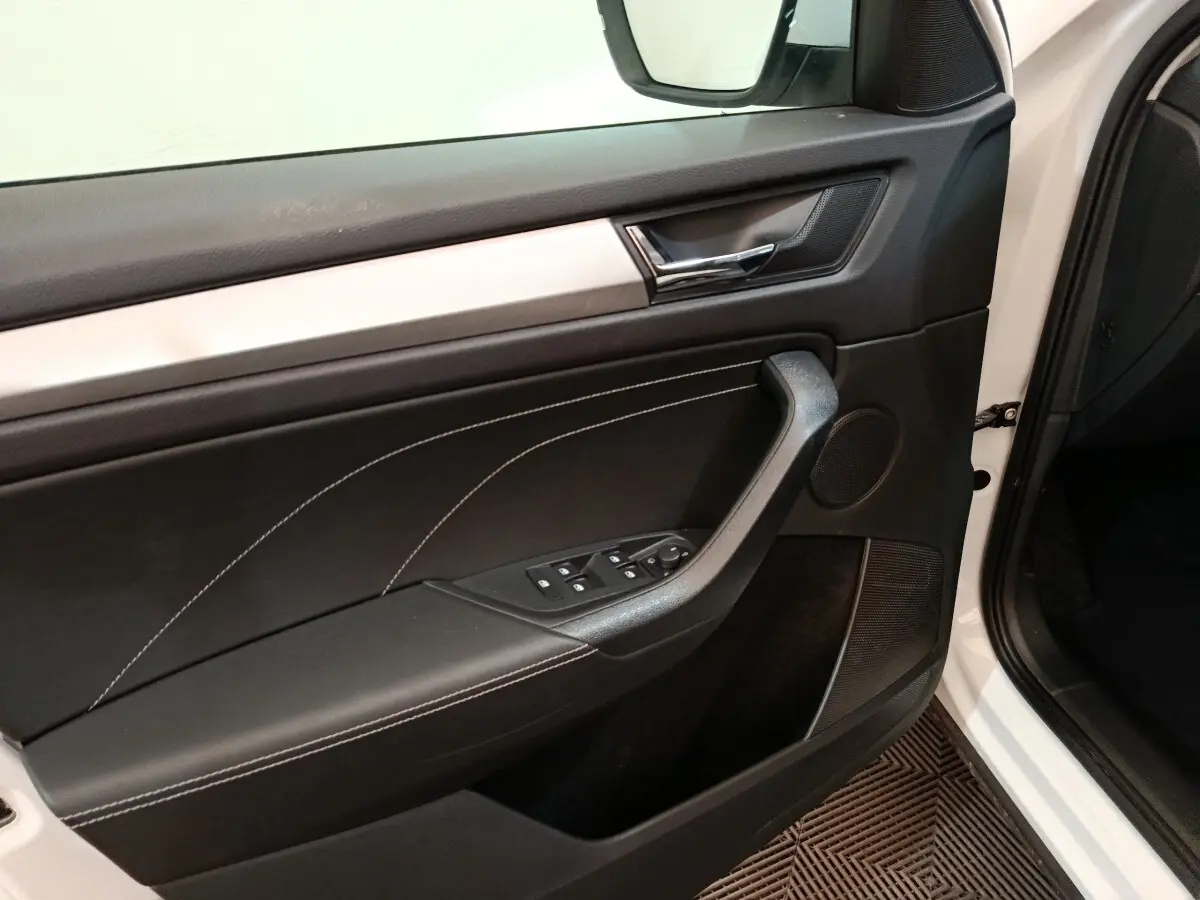 Vue intérieure côté gauche de la porte avant blanche du Skoda Kodiaq 2022 avec garniture noire et surpiqûres blanches.
