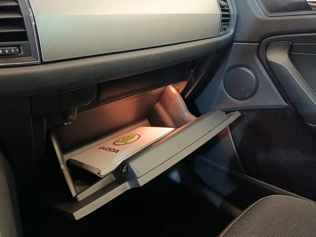 Intérieur du Skoda Kodiaq 2022, vue côté passager sur la boîte à gants ouverte avec manuel Skoda visible.