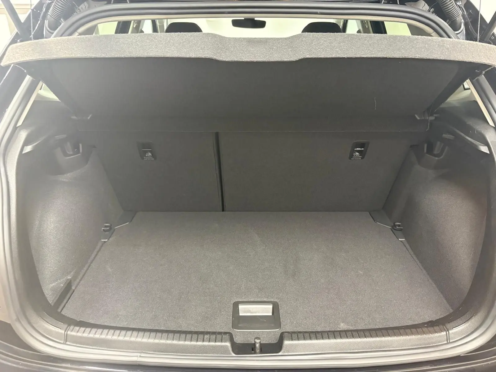 Coffre ouvert de Volkswagen Polo noir intense 2025, vue arrière montrant l'espace de chargement vide et la tablette cache-bagages.