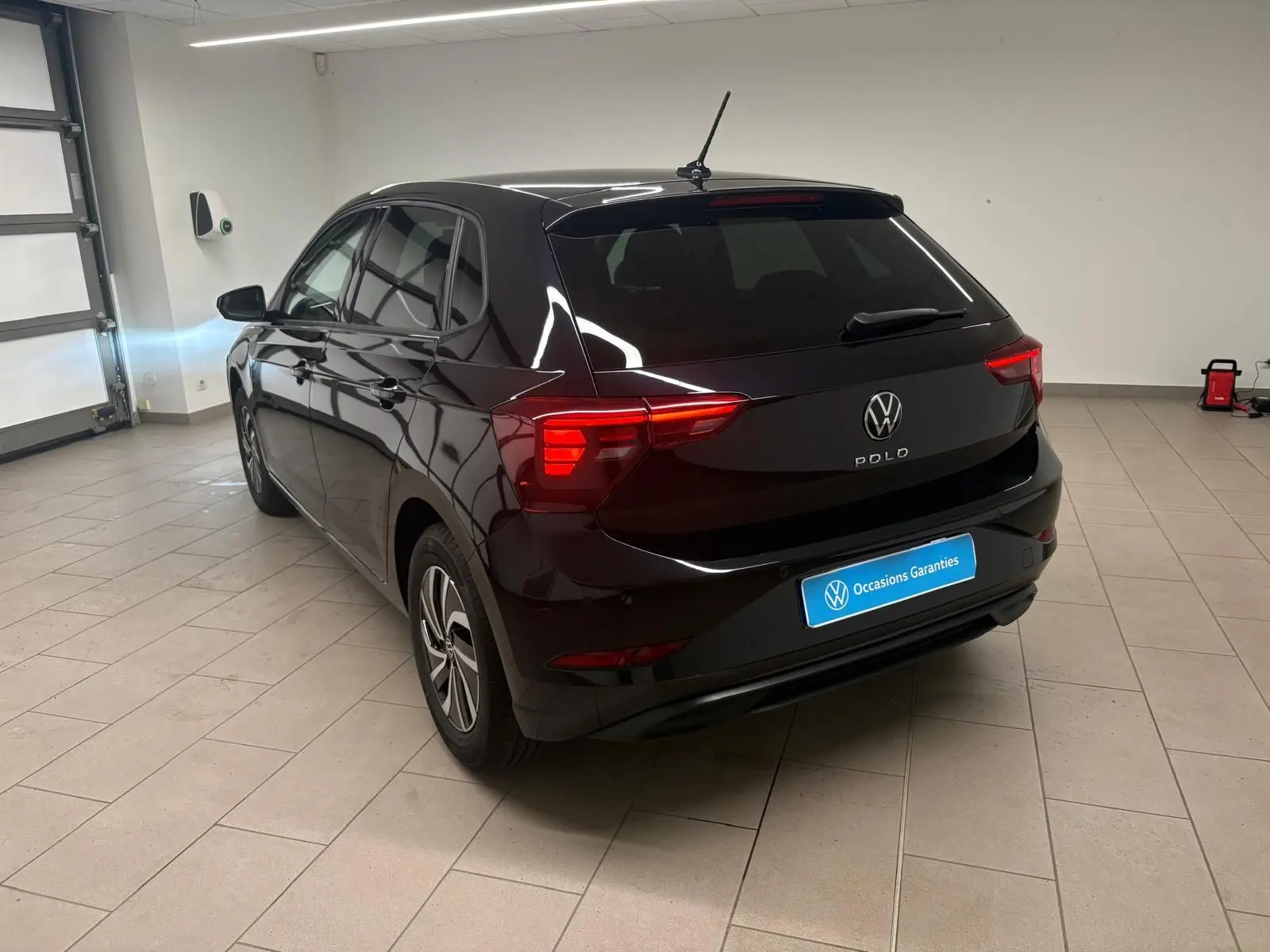 Vue 3/4 arrière droite d'une Volkswagen Polo noire intense avec feux arrière LED, jantes alliage et vitres surteintées.
