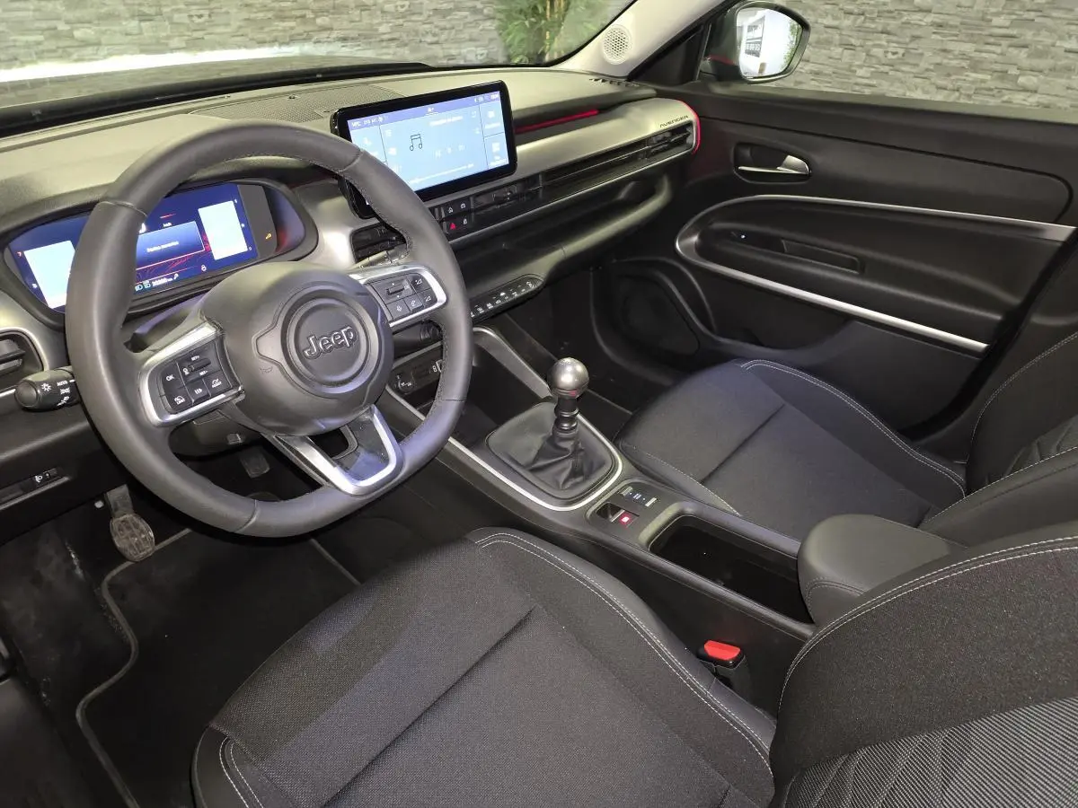 Vue intérieure côté conducteur du Jeep Avenger 2025 noir, avec tableau de bord numérique et écran tactile central.
