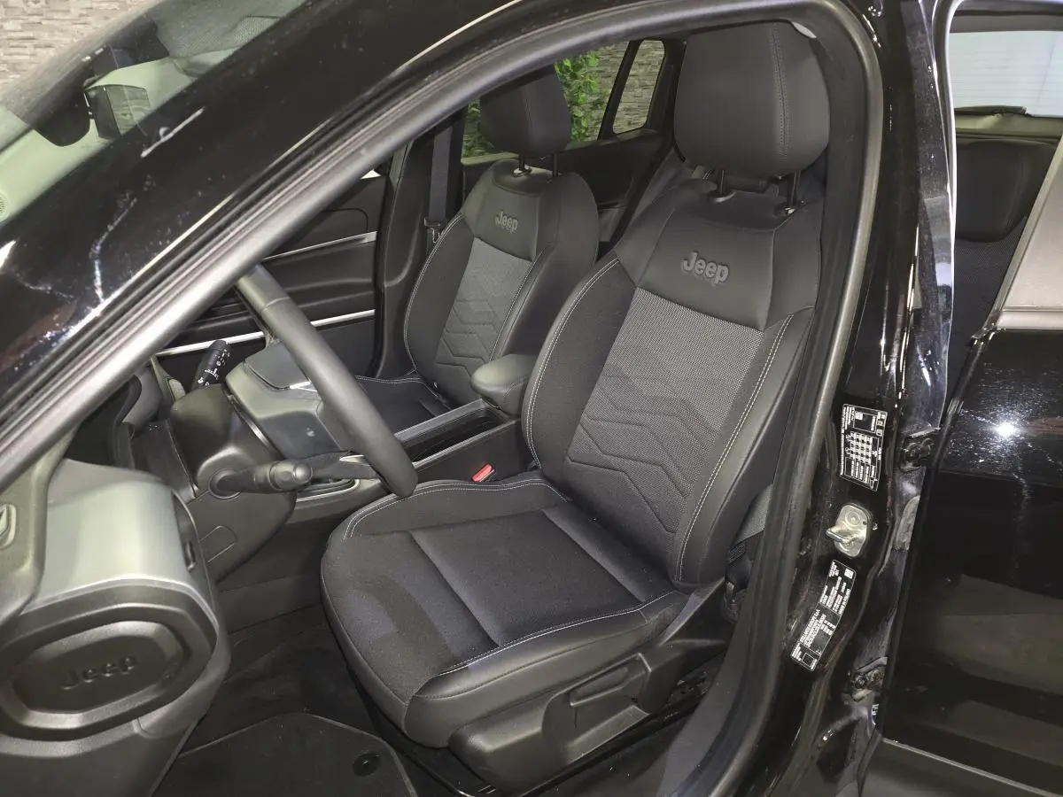 Vue intérieure côté conducteur du Jeep Avenger noir 2025, sièges mixtes tissu/TEP avec logo Jeep brodé.