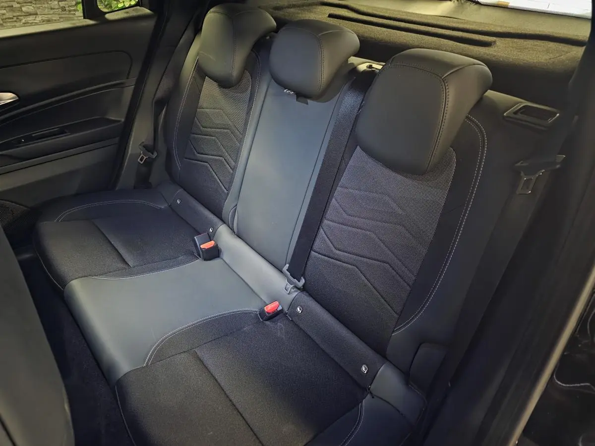 Vue intérieure de la banquette arrière noire du Jeep Avenger 2025 avec appuie-têtes et ceintures visibles.