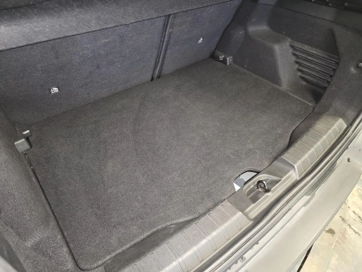 Vue rapprochée du coffre noir du Jeep Avenger 2025, montrant le plancher de coffre modulable et la garniture intérieure.