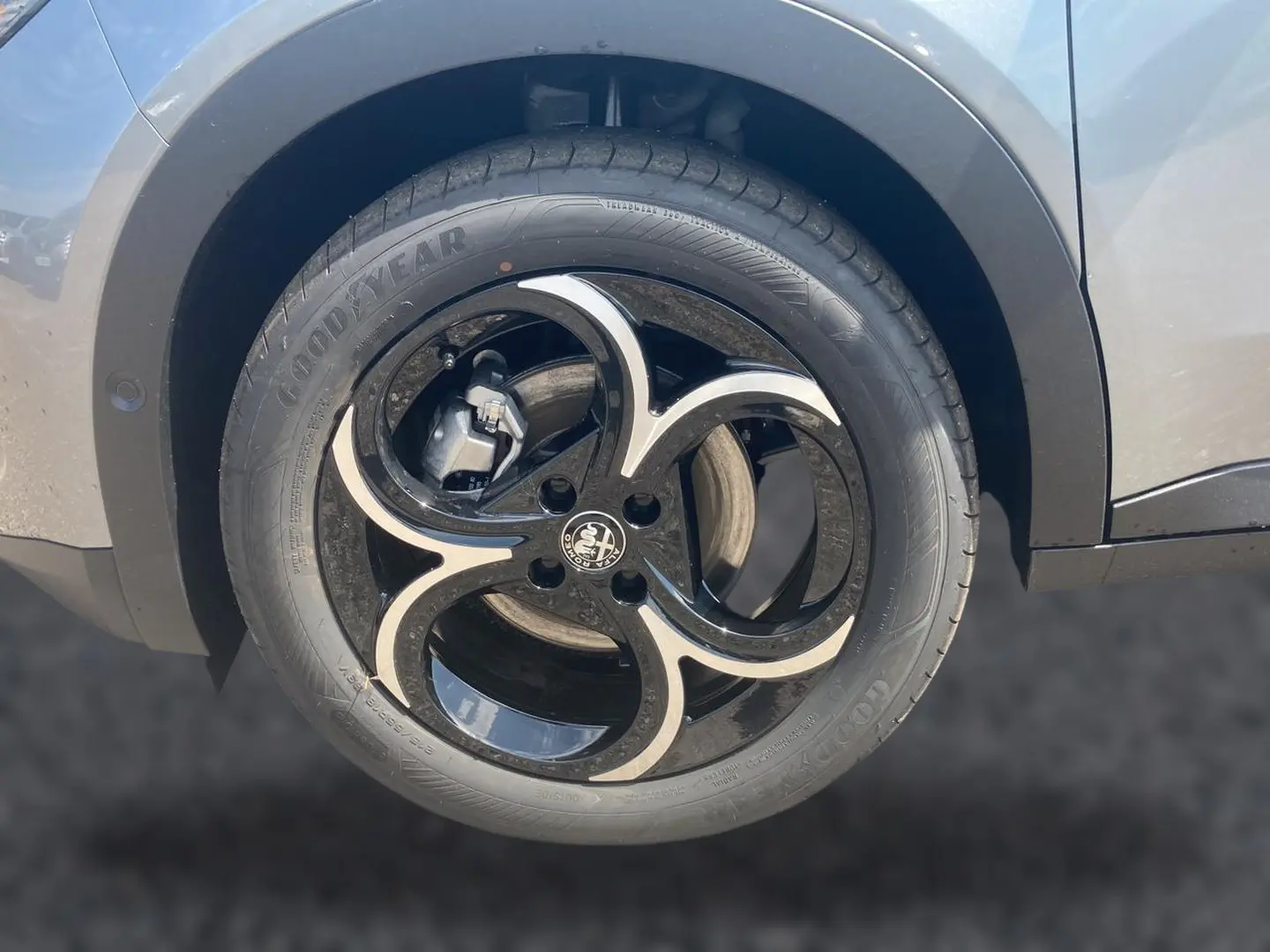Gros plan sur la roue avant droite grise d’une Alfa Romeo Junior 1.2 hybride avec jante alliage noire et argentée.