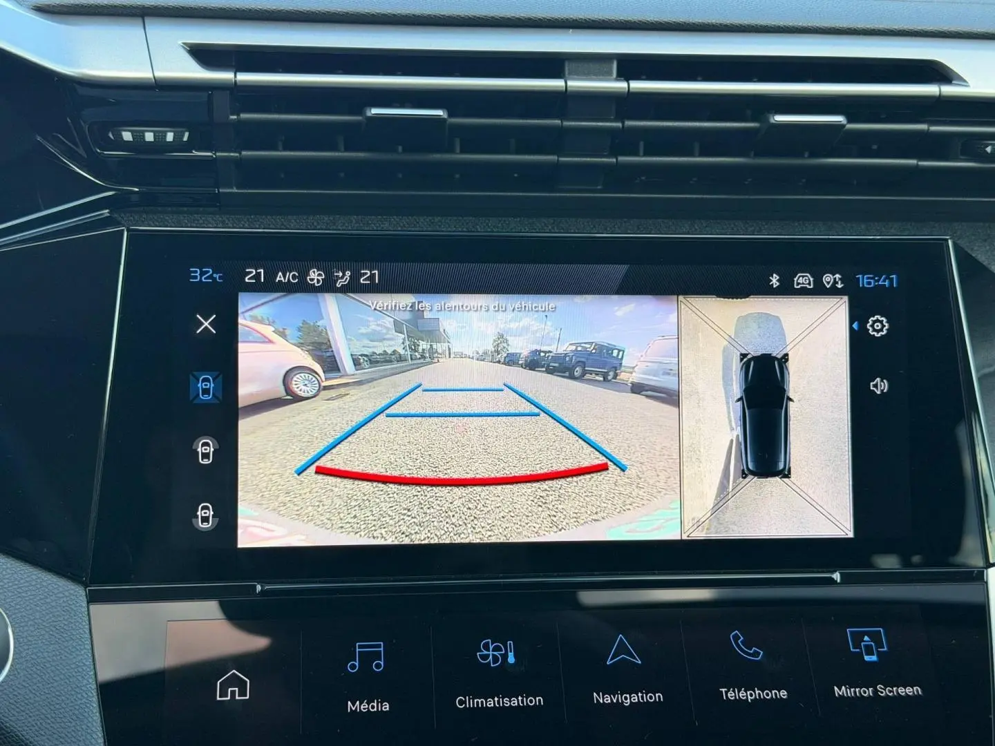 Écran tactile intérieur de la Peugeot 308 rouge Elixir montrant la caméra de recul et l’aide au stationnement.