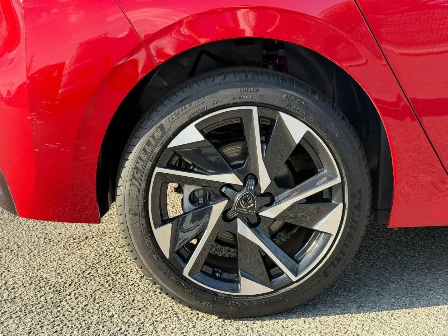 Gros plan sur la jante alu noire et argentée de la roue arrière droite d'une Peugeot 308 rouge Elixir.