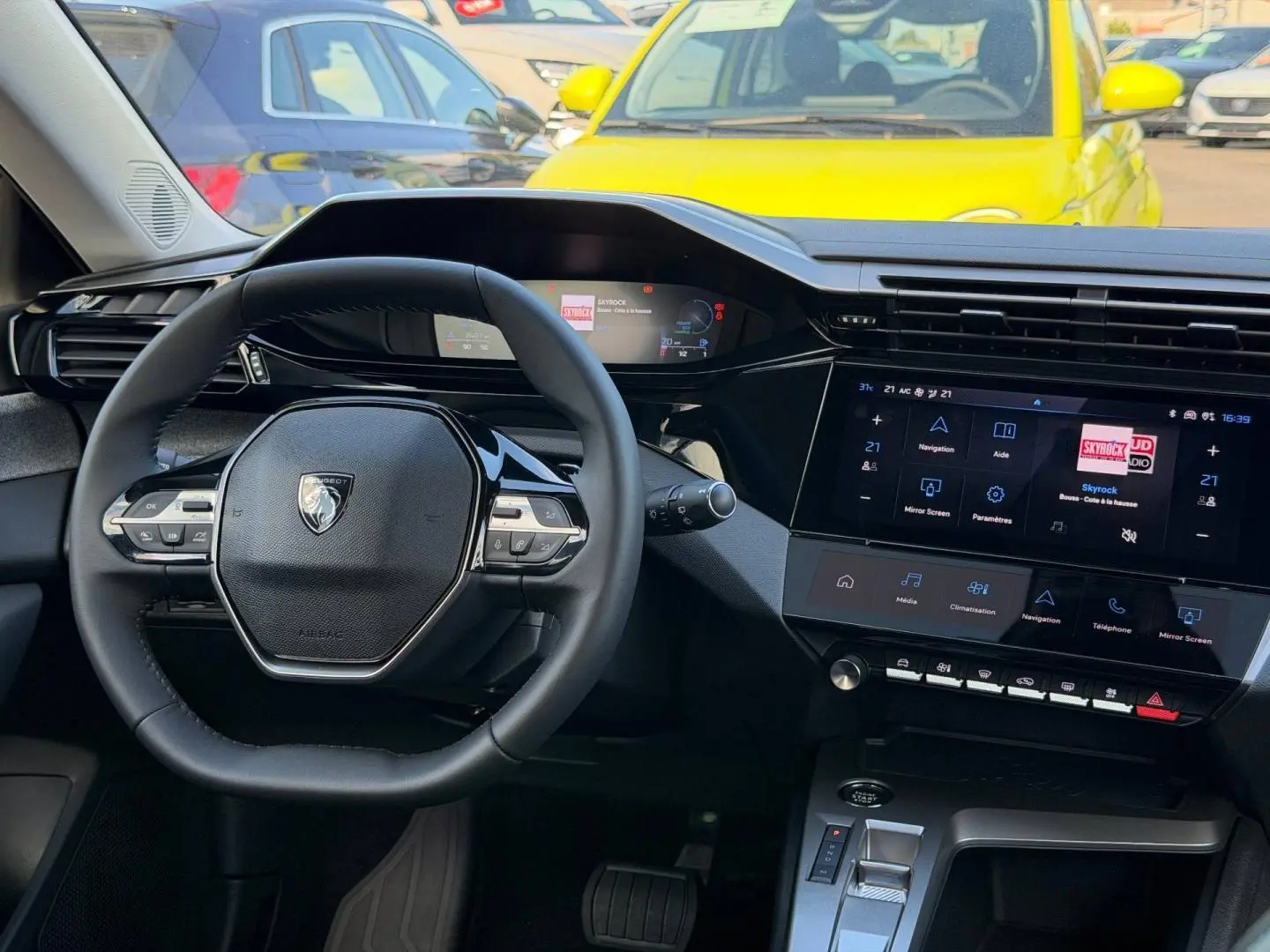 Vue intérieure centrée sur le volant multifonction et l’écran tactile de la Peugeot 308 hybride 2025.