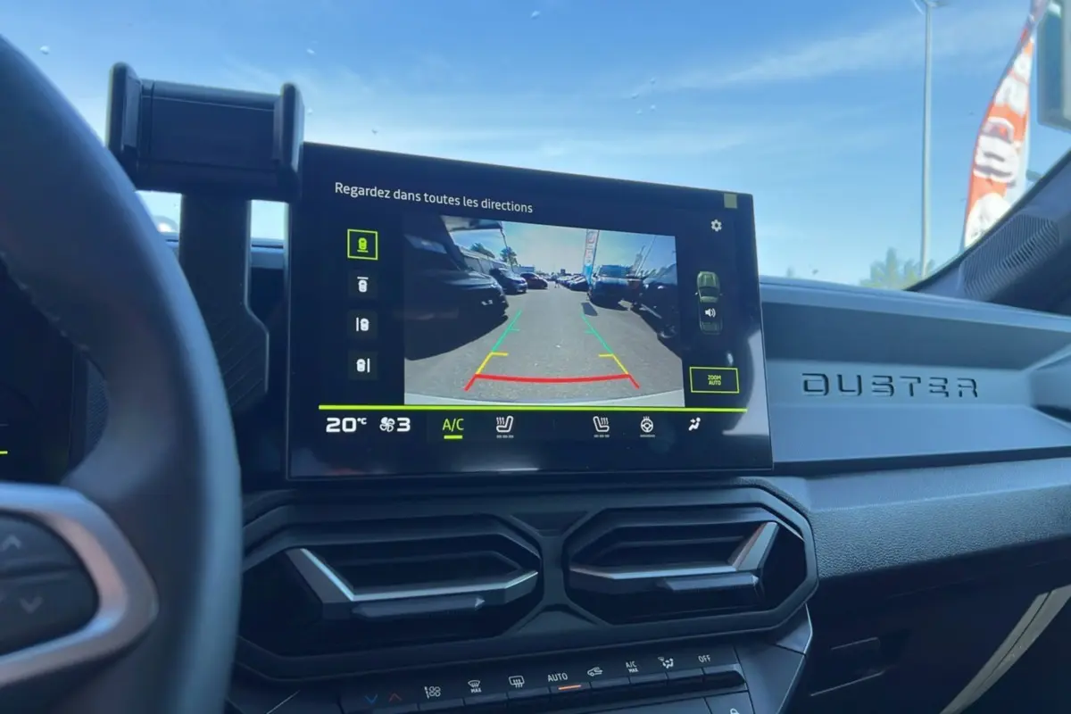 Vue intérieure du tableau de bord du Dacia Duster 2025 avec écran de caméra de recul et logo Duster en relief.