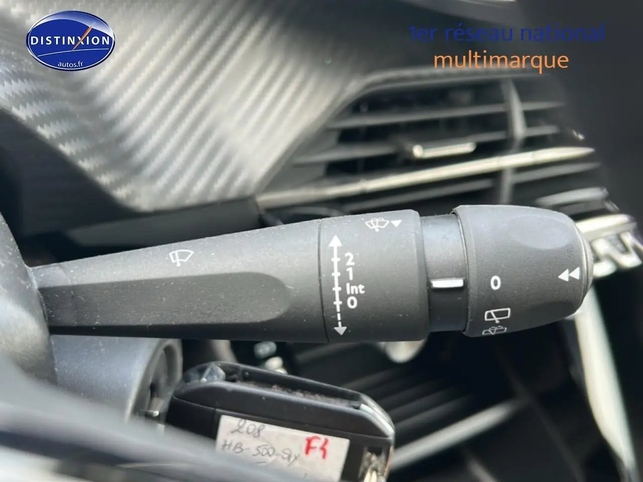 Gros plan sur la commande des essuie-glaces à gauche du volant dans l'habitacle d'une Peugeot 208 gris artense.