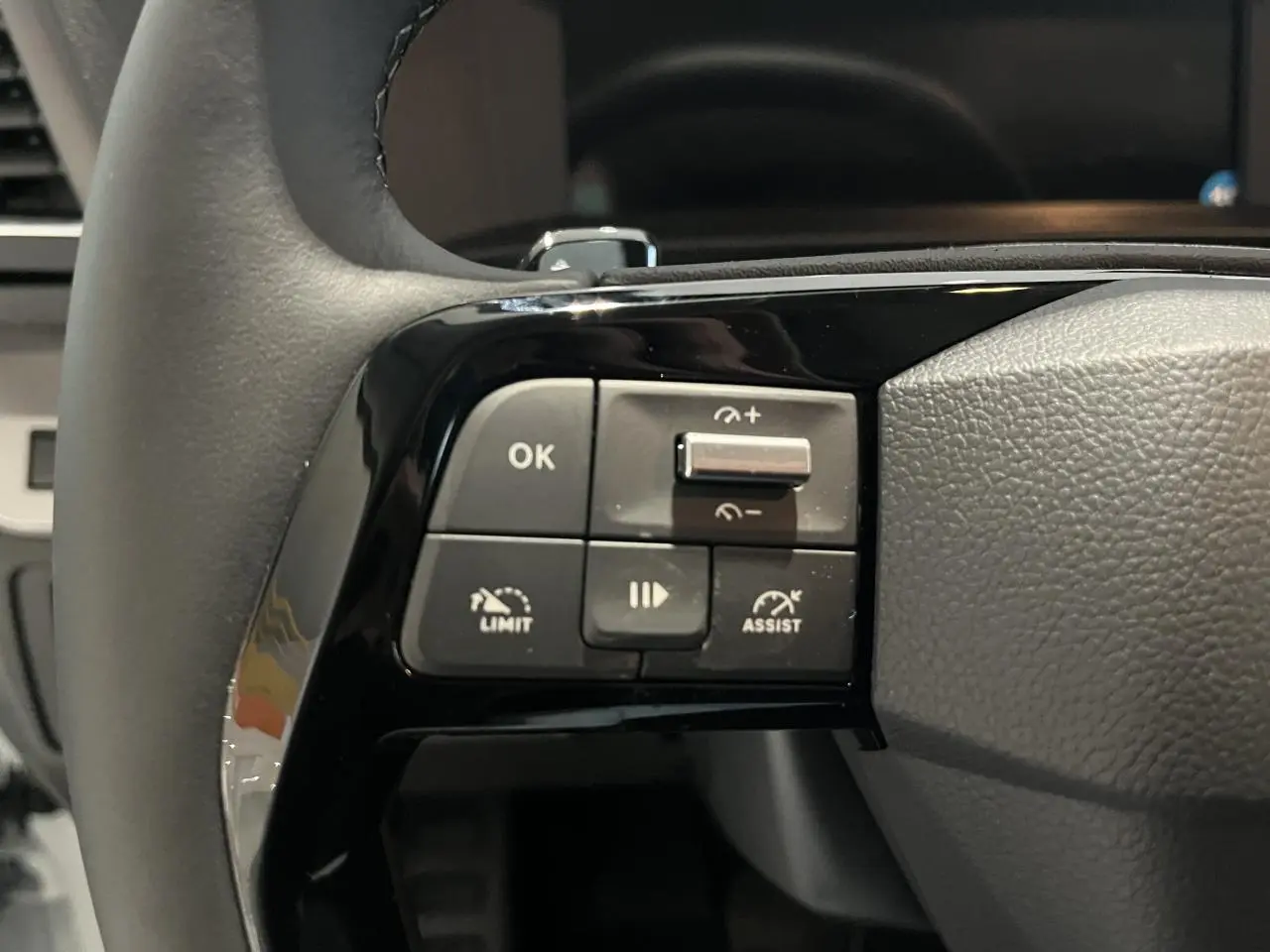 Gros plan sur les commandes gauche du volant en cuir noir du Peugeot Expert Fourgon blanc 2024.