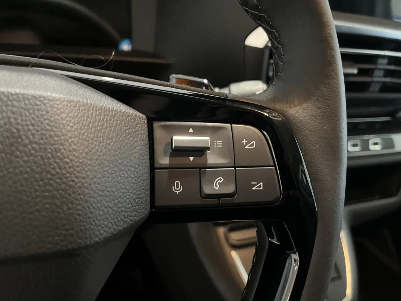 Gros plan sur les commandes au volant cuir noir du Peugeot Expert Fourgon blanc, avec tableau de bord en arrière-plan.