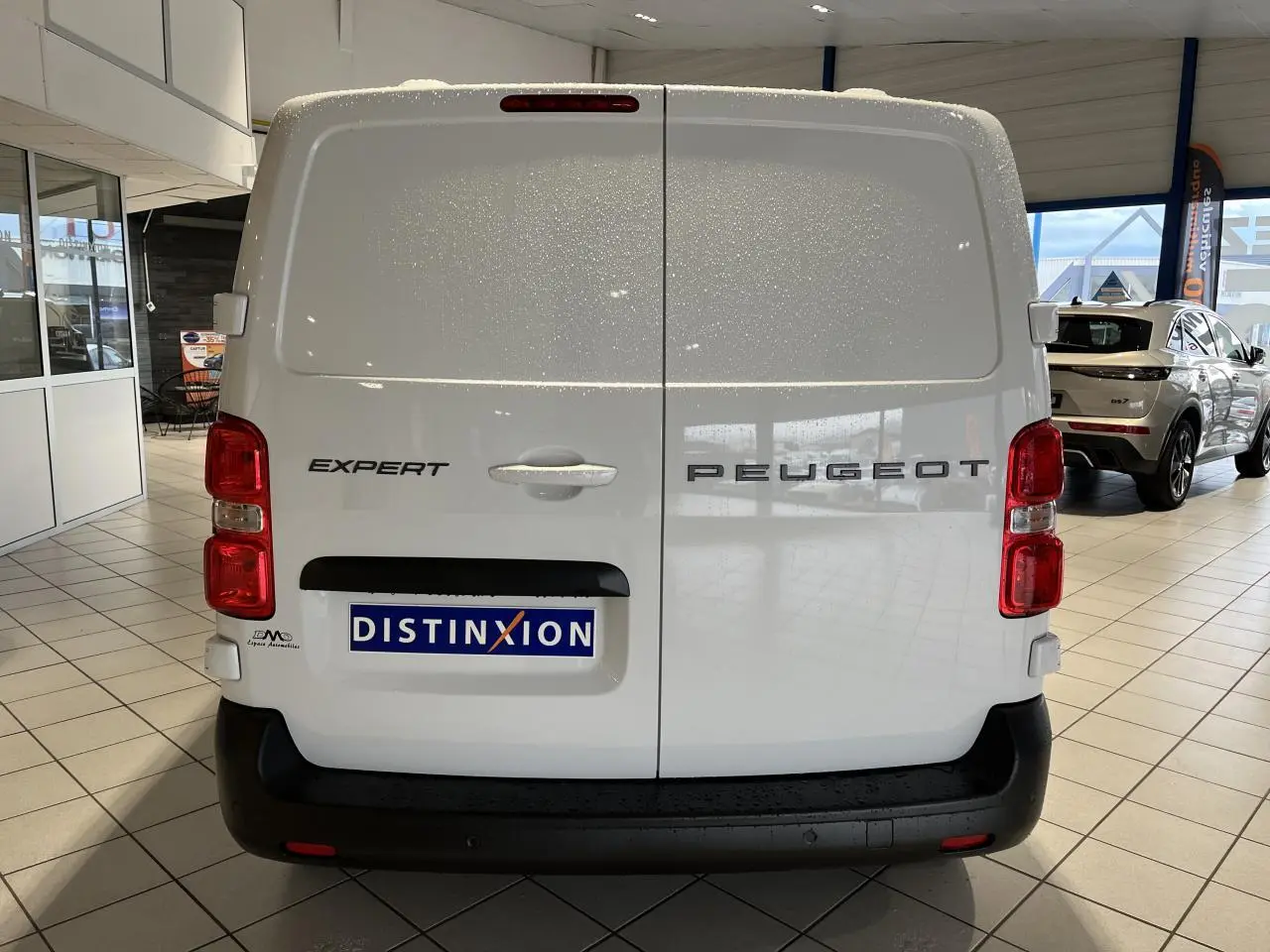 Vue arrière d’un Peugeot Expert Fourgon blanc avec portes battantes et pare-chocs noir en showroom.