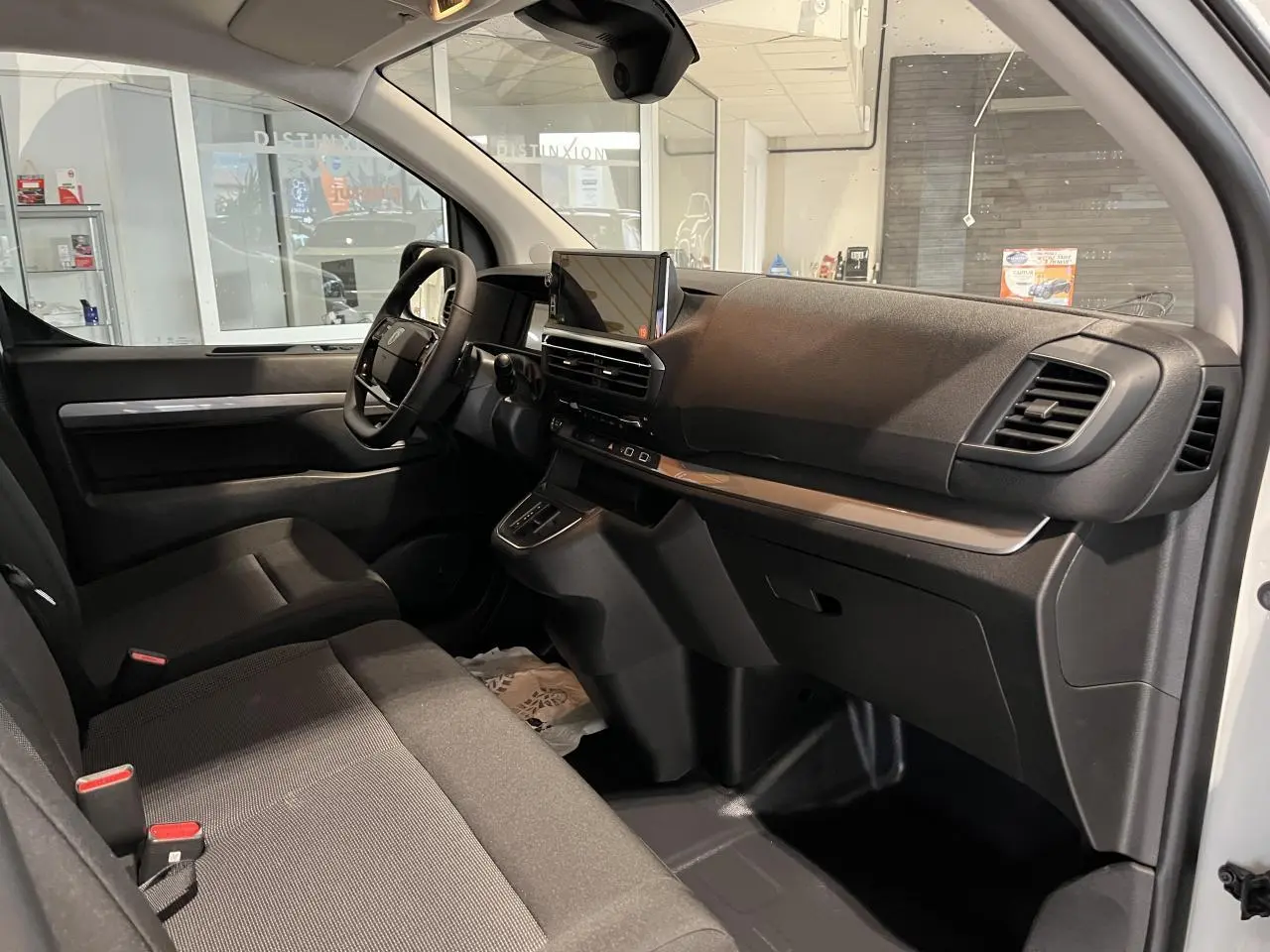 Vue intérieure côté passager du Peugeot Expert Fourgon blanc 2024, avec tableau de bord moderne et sièges tissu bi-ton noir-gris.