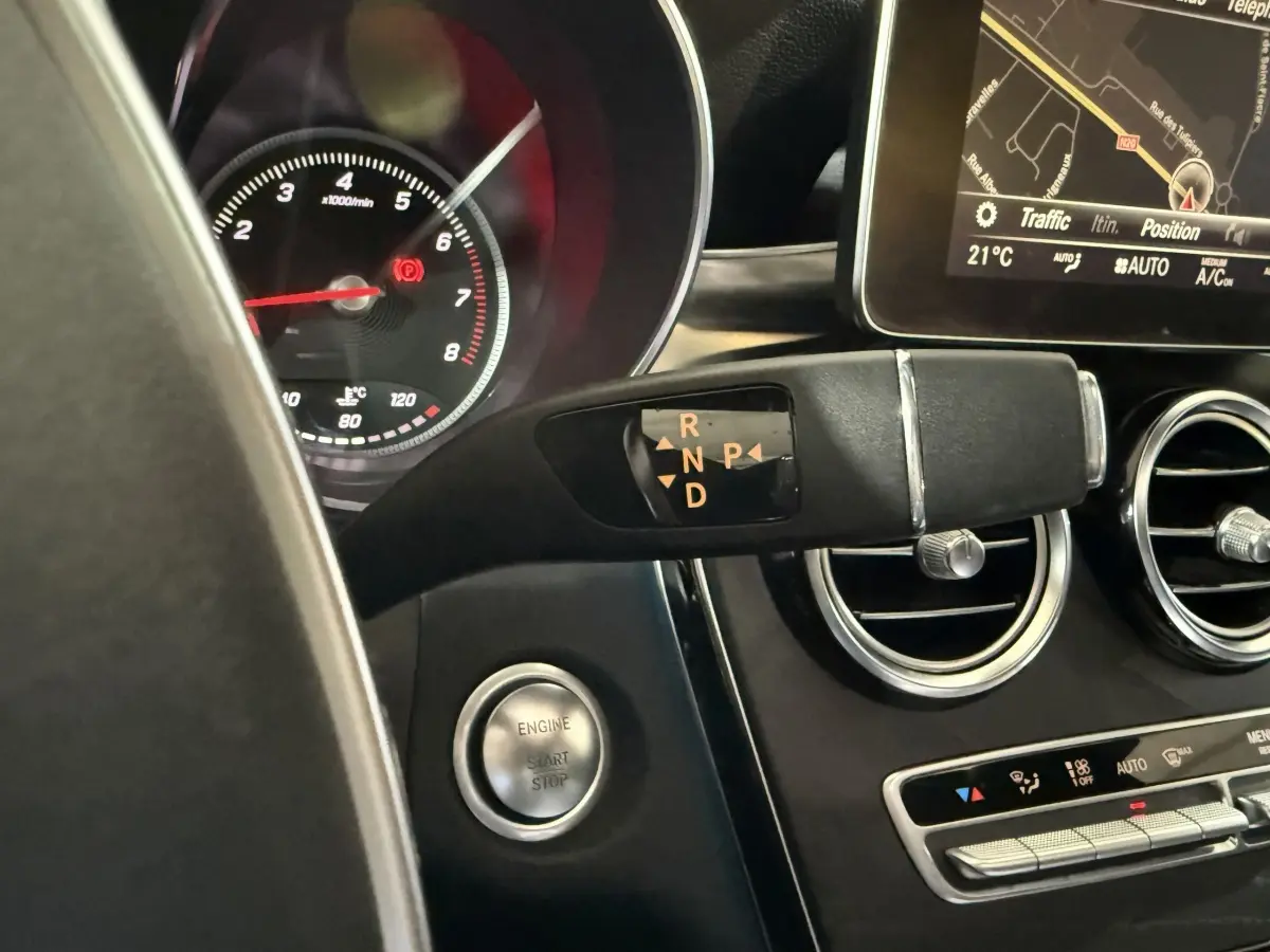 Gros plan sur la commande de boîte automatique et le tableau de bord noir d’un Mercedes GLC 250 Fascination 2019.