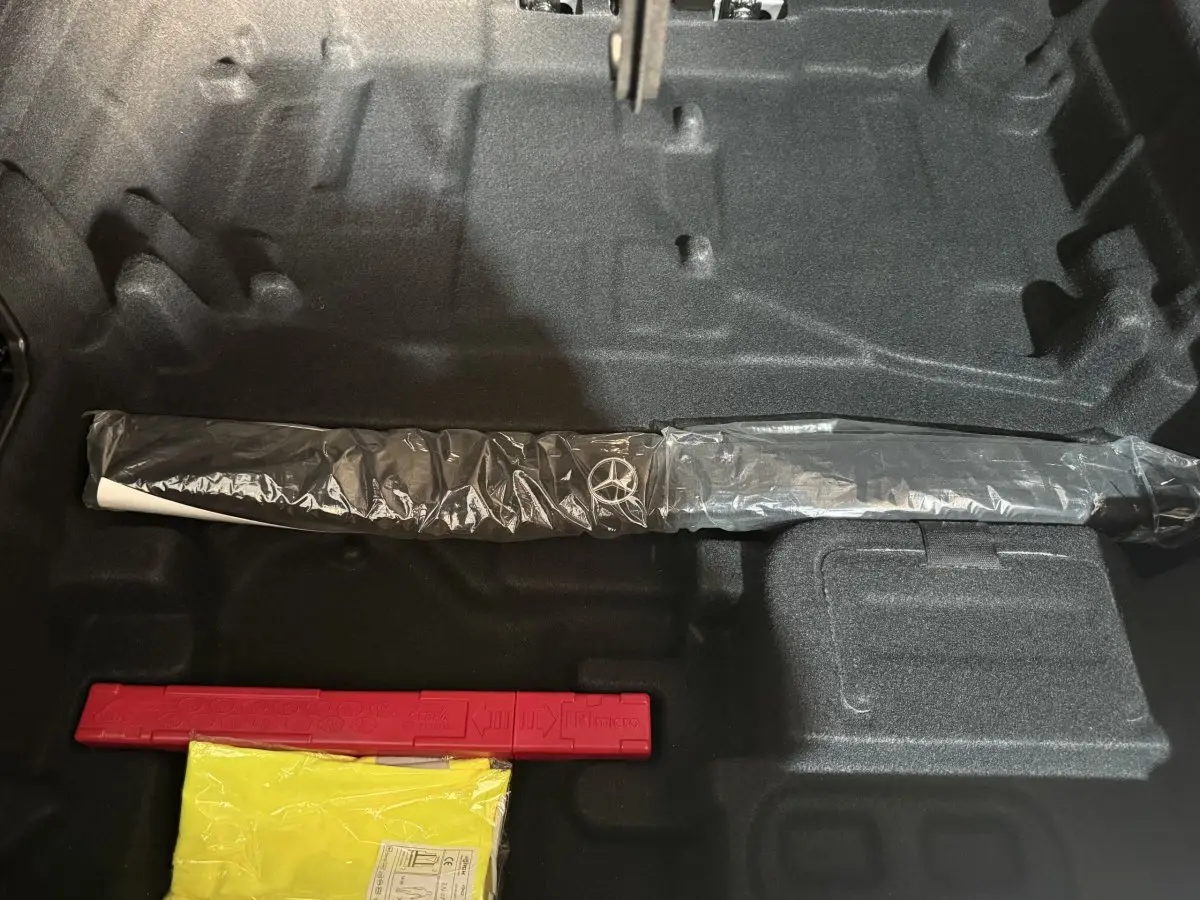 Vue intérieure du coffre d'un Mercedes GLC 250 Fascination 2019 gris foncé, avec un outil Mercedes emballé et un triangle de signalisation rouge.