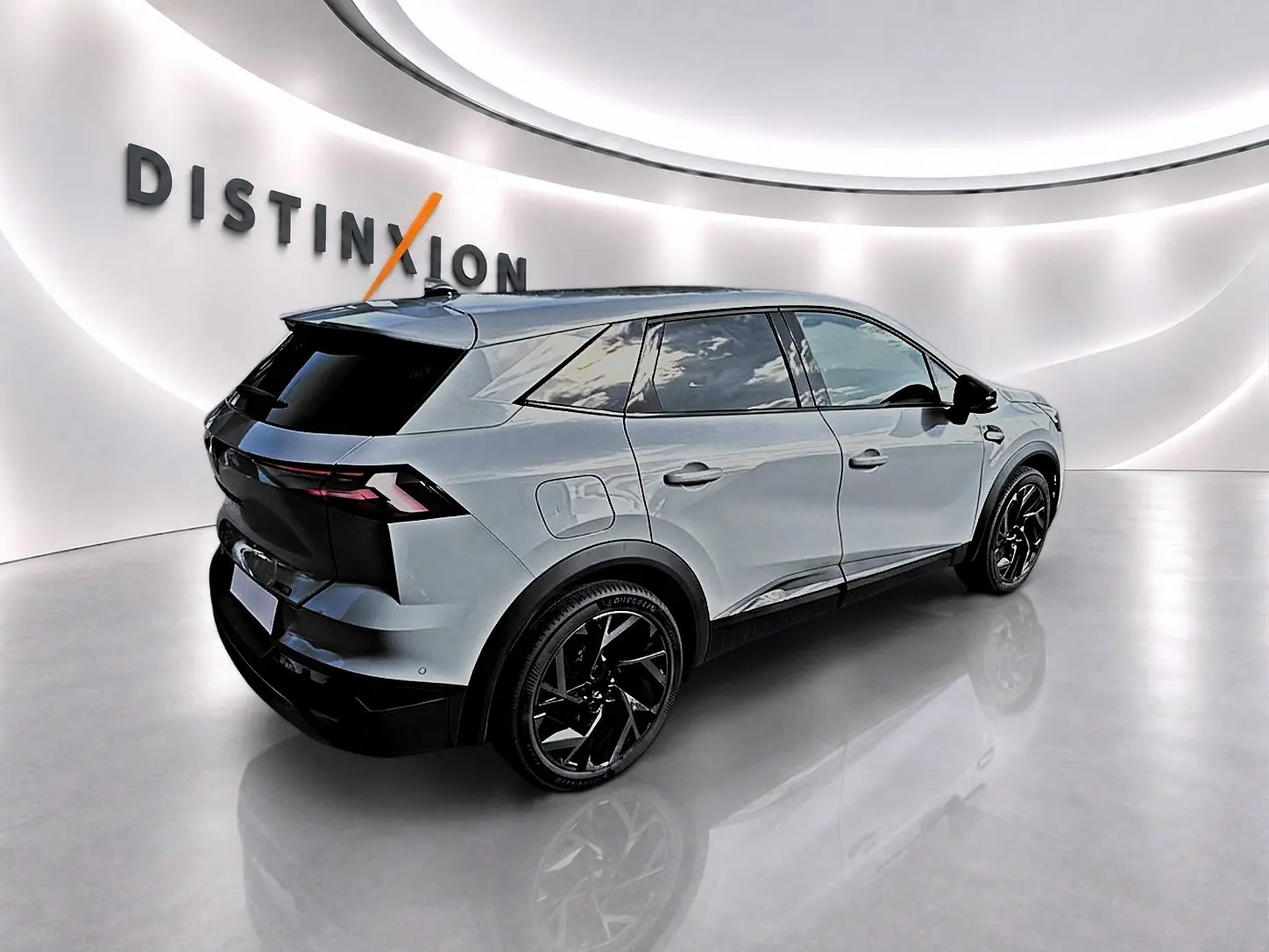Renault Symbioz gris rafale, vue 3/4 arrière droit, jantes noires et vitres arrière surteintées dans un showroom lumineux.