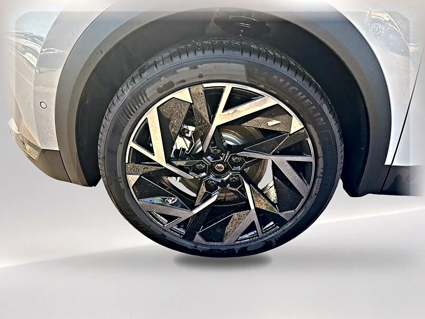 Gros plan sur la roue avant gauche gris rafale du Renault Symbioz 1.8 e-tech avec jante alu noire et argentée au design géométrique.