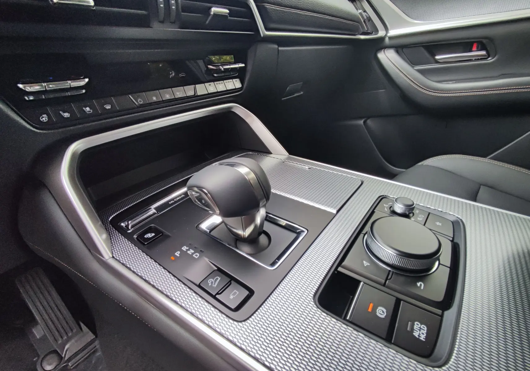 Gros plan sur la console centrale côté conducteur du Mazda CX-60 blanc métal 2024 avec levier de vitesse et commandes intégrées.