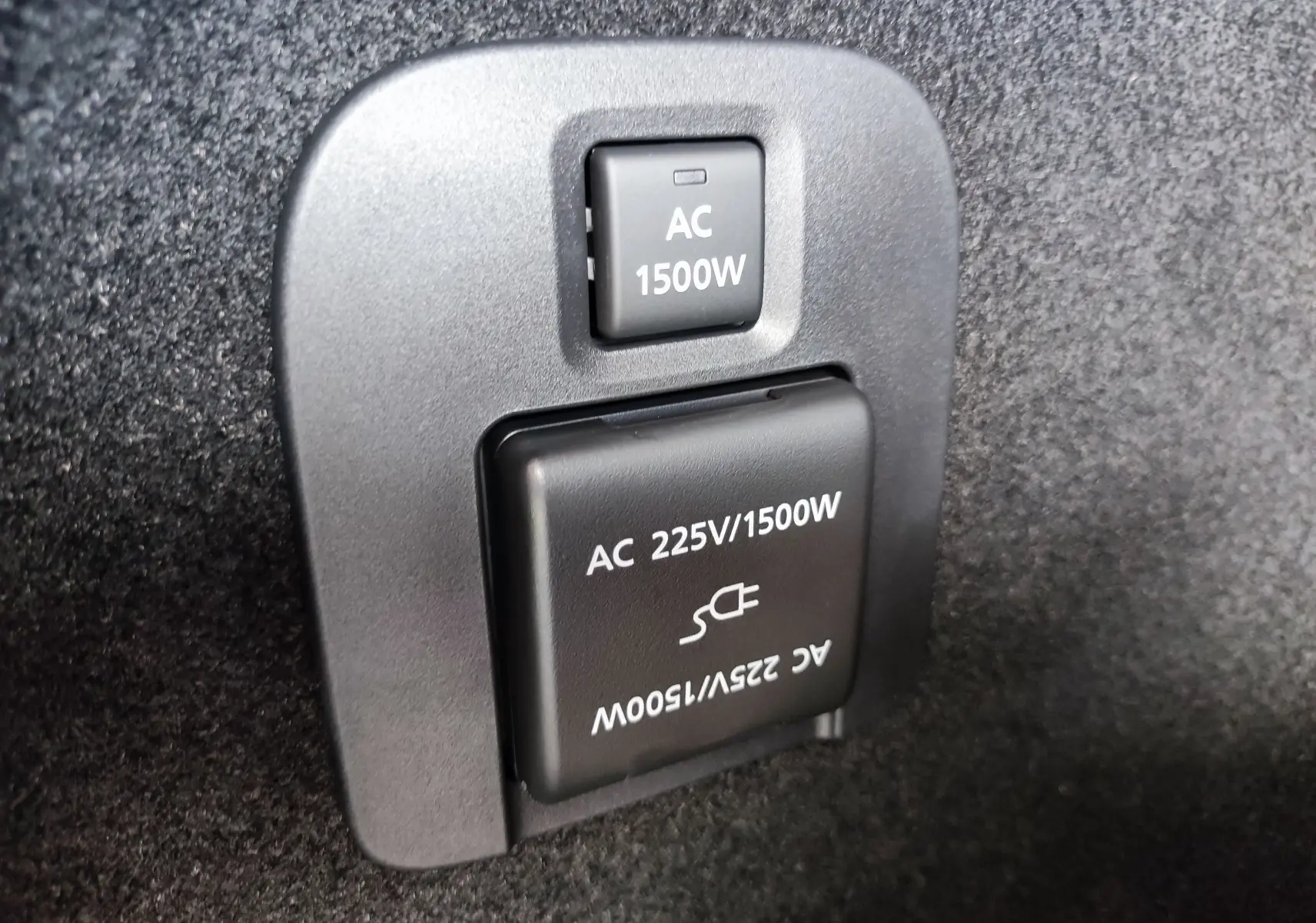 Prise électrique 1500W en gros plan dans le coffre du Mazda CX-60 hybride rechargeable blanc métal 2024.