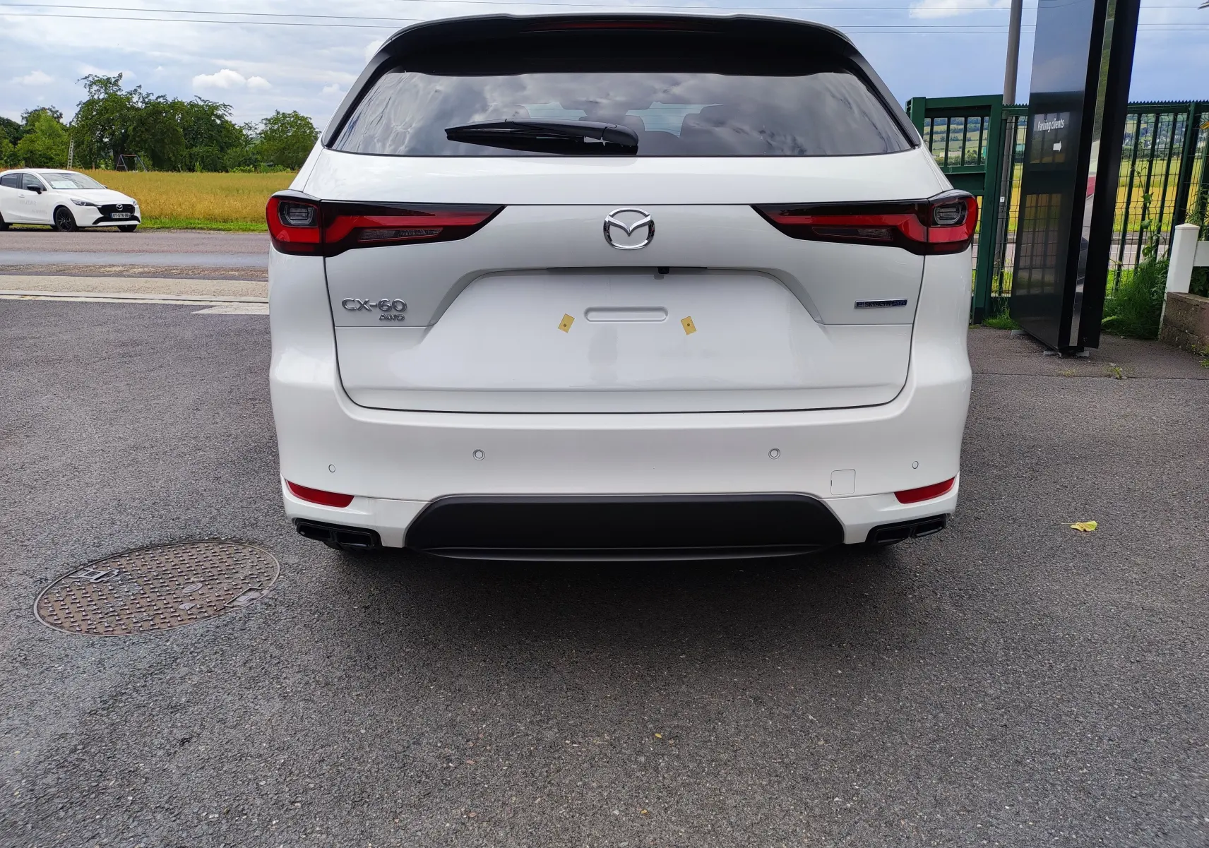 Vue arrière d'un Mazda CX-60 blanc métal 2024 avec feux LED et double sortie d'échappement noire intégrée.