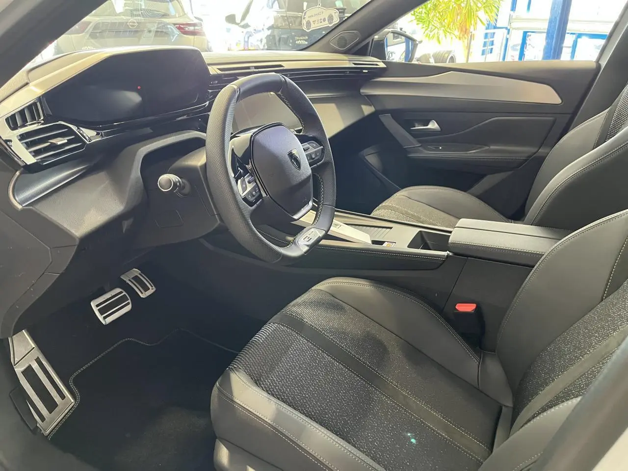 Intérieur avant droit de la Peugeot 308 SW GT 2025 avec sièges noirs et volant cuir multifonction.