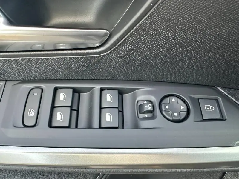 Panneau de commandes des vitres et rétroviseurs côté gauche dans l'habitacle noir du Peugeot 3008 Hybrid 2025.