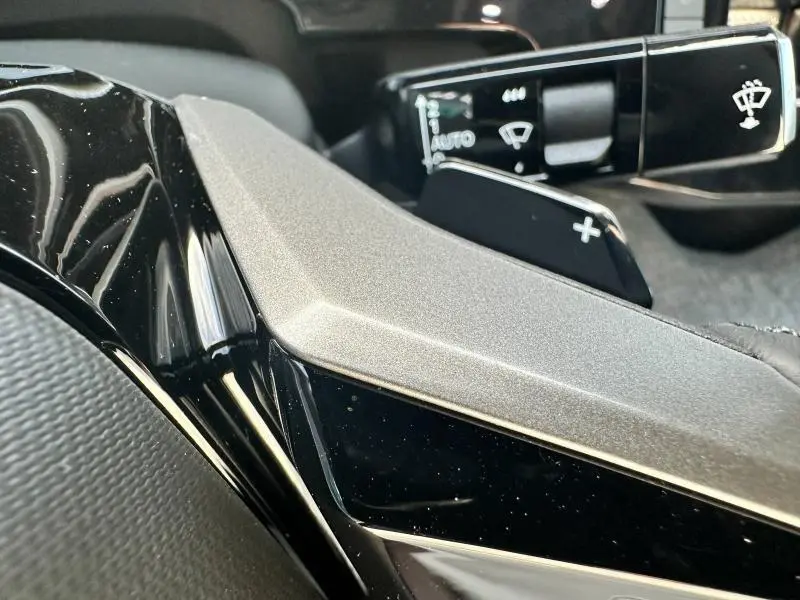 Gros plan sur la commande d'essuie-glace et la palette de changement de vitesse du volant noir du Peugeot 3008 Hybrid 2025.