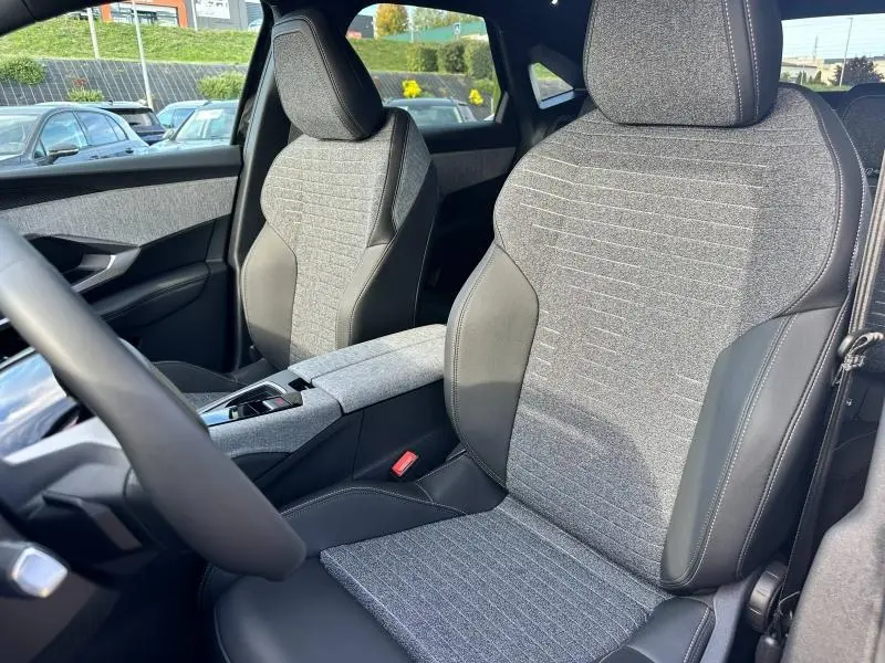 Gros plan sur les sièges avant en tissu gris et cuir noir du Peugeot 3008 Hybrid 2025, intérieur moderne et soigné.