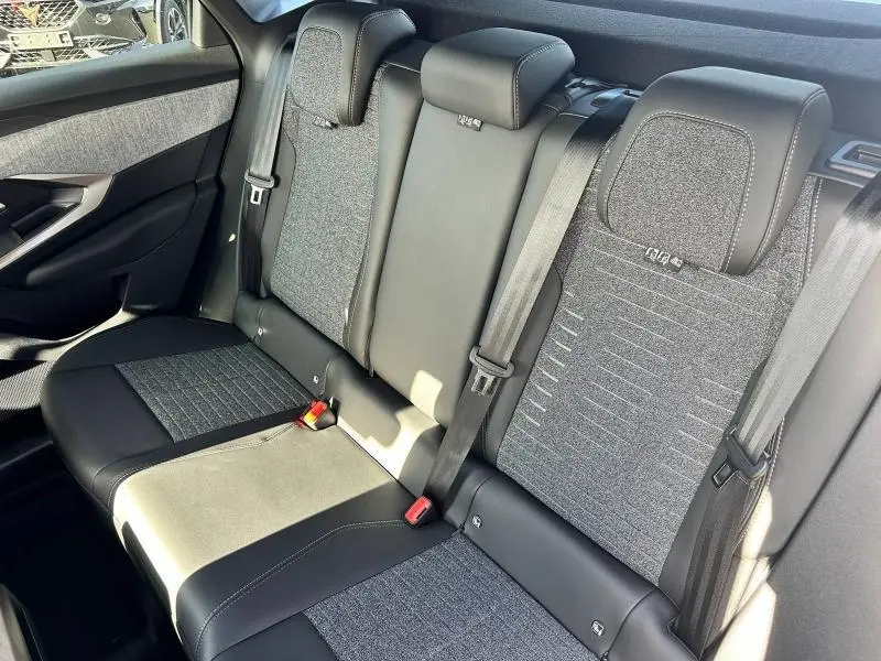Vue rapprochée de la banquette arrière du Peugeot 3008 2025, tissu gris et cuir noir avec ceintures de sécurité visibles.