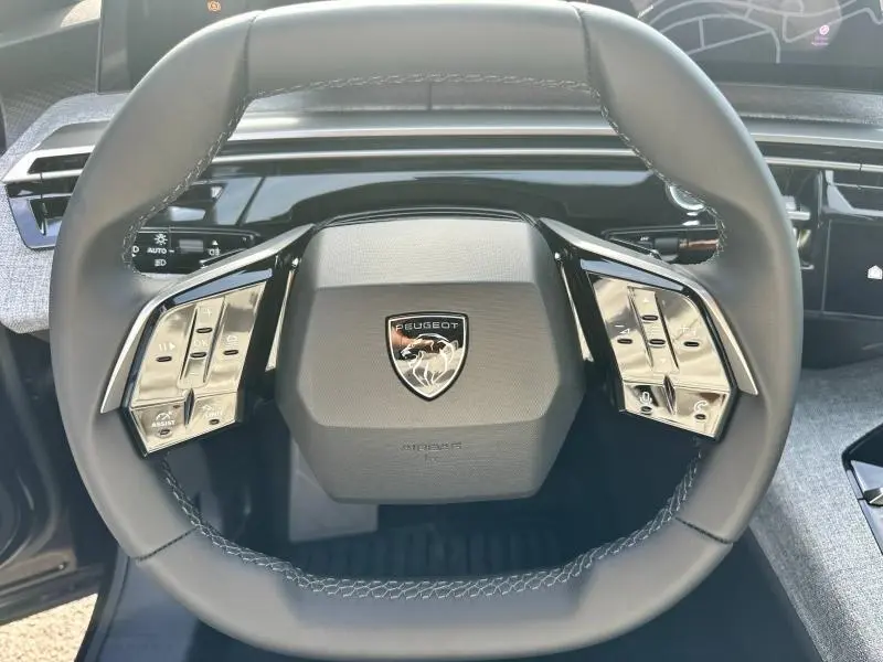 Volant cuir noir de Peugeot 3008 2025 avec commandes intégrées et logo lion au centre, vue frontale rapprochée.