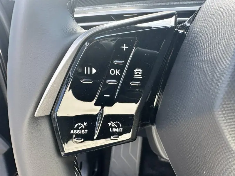 Gros plan sur les commandes noires au volant cuir du Peugeot 3008 Hybrid 2025, avec boutons multifonctions et régulateur.